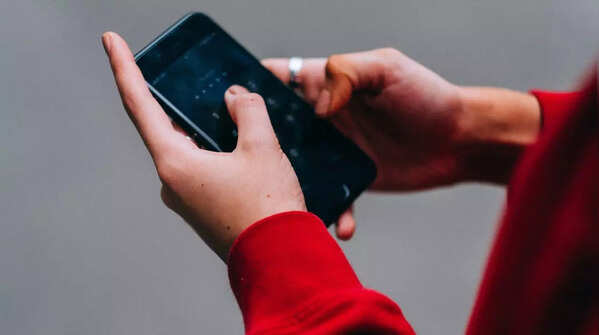 Hands holding phone, typing with both thumbs.